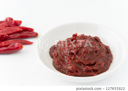 Red chili peppers and bean paste in a small dish on a white background 127655822