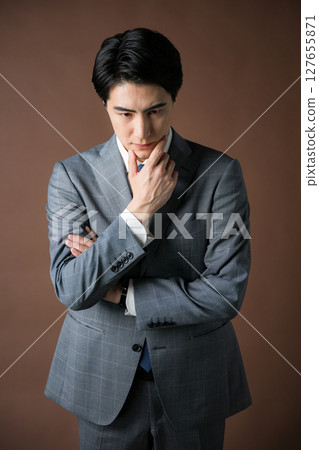 Image of a worried businessman president wearing a suit on a brown background, planning strategy and tactics Image of a worried businessman president wearing a suit on a brown background, planning strategy and tactics 127655871