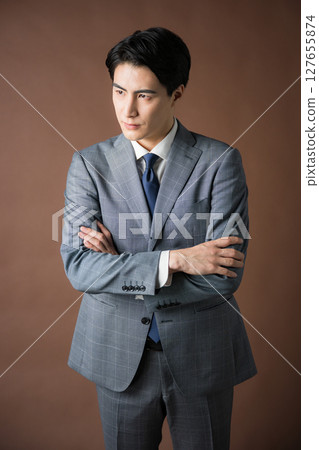 Image of a worried businessman president wearing a suit with his arms folded against a brown background, planning strategy and tactics 127655874