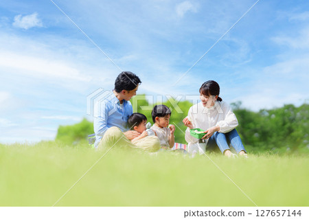 Family of four having a picnic in the park Family of four having a picnic in the park 127657144