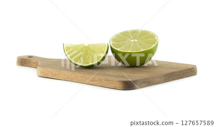 Fresh lime cut in half and slice on wooden cutting board 127657589