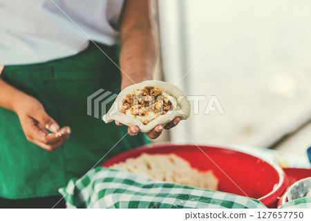 Elaboration of traditional pupusas. Hands of saleswoman preparing raw pupusa 127657750
