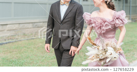 A couple walking through the garden of a Western-style house in pink dresses taking wedding photos A couple walking through the garden of a Western-style house in pink dresses taking wedding photos 127658229