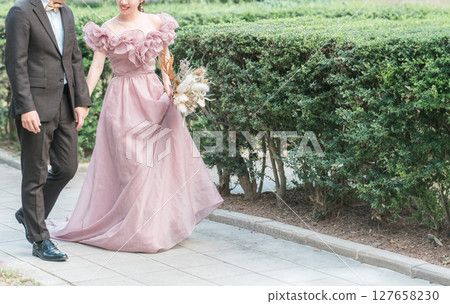 A couple walking through the garden of a Western-style house in pink dresses taking wedding photos A couple walking through the garden of a Western-style house in pink dresses taking wedding photos 127658230