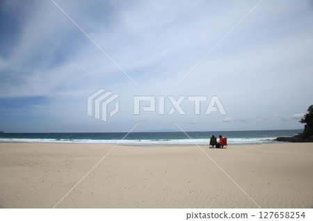 Couple with waves crashing on the beach Couple with waves crashing on the beach 127658254