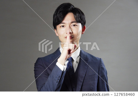 Businessman secret pose black background 127658460