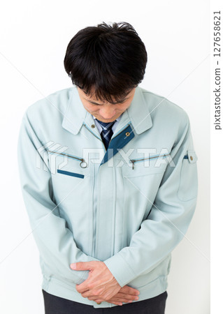 A middle-aged male businessman wearing green work clothes apologizing A middle-aged male businessman wearing green work clothes apologizing 127658621