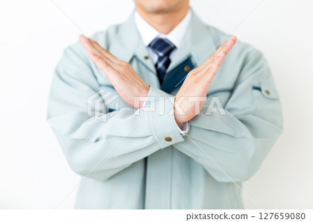 A middle-aged male businessman wearing green work clothes making a cross sign 127659080