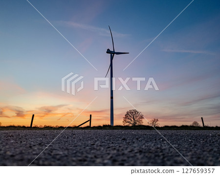 A Stunning Wind Turbine Silhouette Against a Breathtaking Sunset Sky with Vibrant Colors 127659357