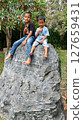 two boys sitting on a big rock 127659431