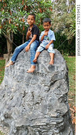 two boys sitting on a big rock two boys sitting on a big rock 127659431