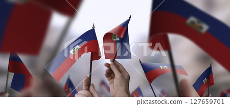 Haiti flags in their hands on a blurred urban background 127659701