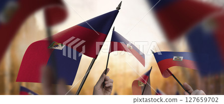 Haiti flags in their hands on a blurred urban background 127659702