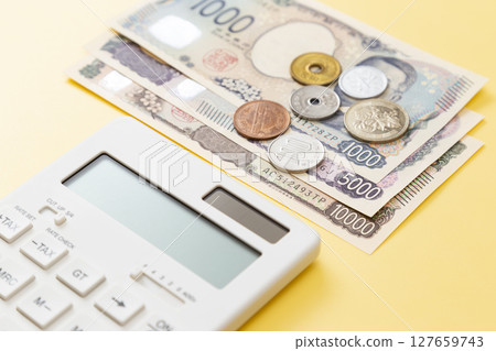 Japanese money and calculator on a yellow background 127659743
