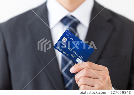 Businessman in a suit holding a credit card Businessman in a suit holding a credit card 127659848