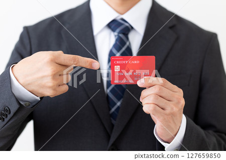 一位西裝筆挺的商人指著一張信用卡 一位西裝筆挺的商人指著一張信用卡 127659850