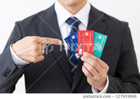 一位西裝筆挺的商人指著一張信用卡 一位西裝筆挺的商人指著一張信用卡 127659986
