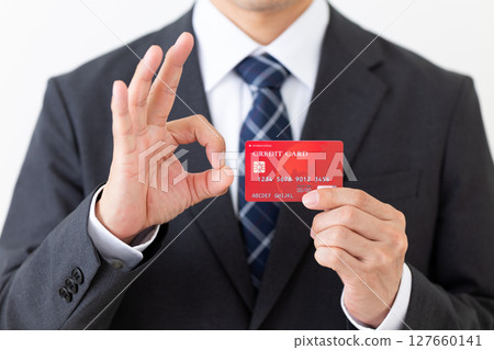 一位西裝革履的商人拿著信用卡，做著圓圈手勢 127660141