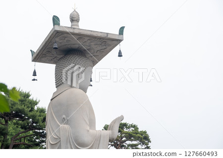 Mireuk Daebul statue of the bodhisattva Maitreya at Bongeunsa Temple, a Buddhist temple in Seoul. With background of green leaves in summer. It is the tallest stone statue in Korea. Mireuk Daebul statue of the bodhisattva Maitreya at Bongeunsa Temple, a Buddhist temple in Seoul. With background of green leaves in summer. It is the tallest stone statue in Korea. 127660493