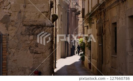 Narrow alley in Tropea, Calabria, featuring ancient stone buildings and a pedestrian Narrow alley in Tropea, Calabria, featuring ancient stone buildings and a pedestrian 127660786