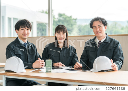 Male and female businessmen in work clothes having a meeting while looking at a model of a building 127661186