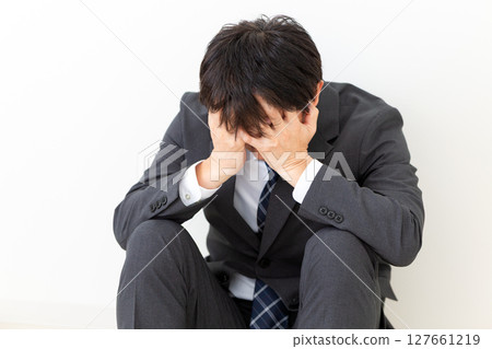 A middle-aged male businessman in a suit suffering from depression 127661219