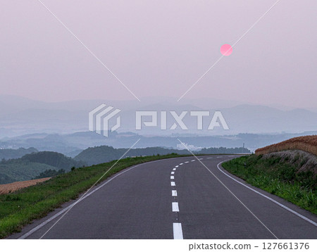 A view of the sun setting over a hilltop road in Biei, Hokkaido A view of the sun setting over a hilltop road in Biei, Hokkaido 127661376