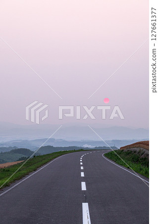 A view of the sun setting over a hilltop road in Biei, Hokkaido A view of the sun setting over a hilltop road in Biei, Hokkaido 127661377