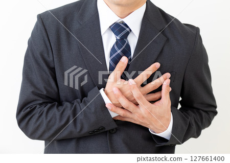 A middle-aged male businessman in a suit suffering while holding his chest A middle-aged male businessman in a suit suffering while holding his chest 127661400