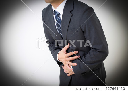 A middle-aged male businessman in a suit suffering from stomach pain A middle-aged male businessman in a suit suffering from stomach pain 127661410