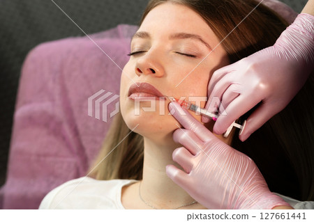 Clinic specialist performs precise lip filler injection on patient Clinic specialist performs precise lip filler injection on patient 127661441