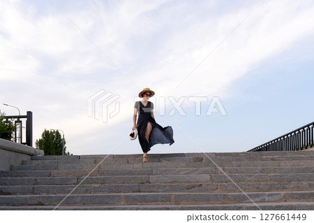 Woman in polka dot dress descends stone steps at sunset Woman in polka dot dress descends stone steps at sunset 127661449