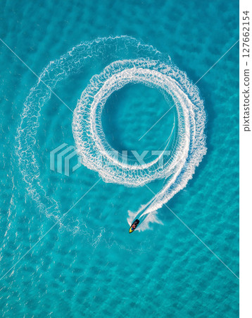 Watercraft Creates Circular Wake in Clear Blue Waters Near a Tropical Beach 127662154