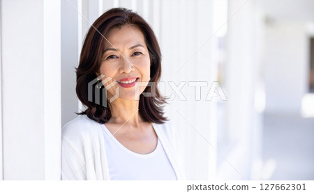 一位面帶微笑的中年婦女靠在牆上的肖像 127662301