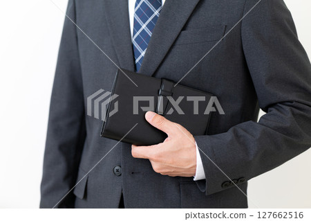 一位身穿西裝、手持黑色筆記本的中年男性商人 127662516