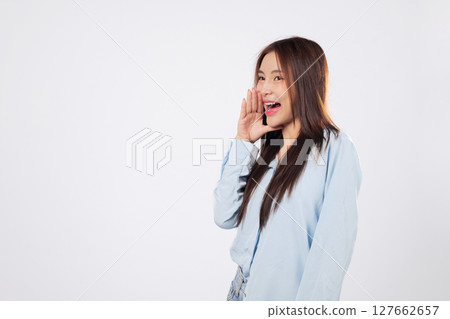 Excited woman shouting loudly with hands over mouth, second woman reacts to news with cheerful expression, both full of emotion on isolated white studio background. 127662657