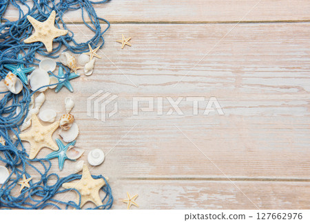 Fishing net, starfishes and seashells lying on wooden planks background Fishing net, starfishes and seashells lying on wooden planks background 127662976