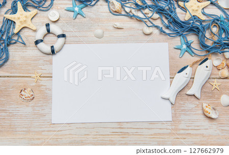 Nautical themed background with blank paper, seashells, starfishes, fishing net and decorative fish Nautical themed background with blank paper, seashells, starfishes, fishing net and decorative fish 127662979