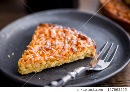 Sweet almond pie on plate on wooden table. 127663235