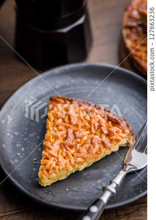 Sweet almond pie on plate on wooden table. 127663236