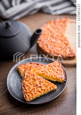 Sweet almond pie on plate on wooden table. 127663237