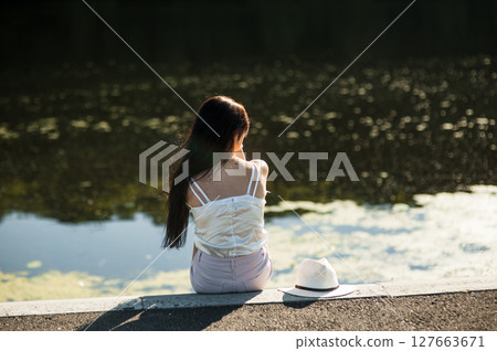 A girl relaxing in the sun by the lake 127663671