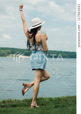 The girl is standing with her face turned to the lake and her back to the camera The girl is standing with her face turned to the lake and her back to the camera 127663681