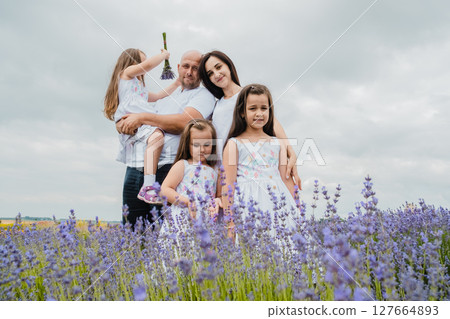 A mother in a white dress is hugging her husband, who is holding a cute little girl A mother in a white dress is hugging her husband, who is holding a cute little girl 127664893