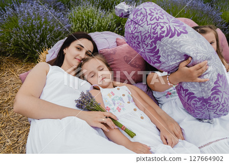 The mother and her daughters are resting in the lavender field. A beautiful bed with cute pillows in the lavender field 127664902
