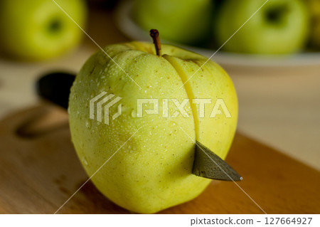 A beautiful green apple with a knife 127664927