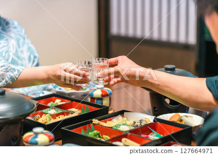 一對夫婦在懷石料理晚餐上用冰涼的清酒杯敬酒 一對夫婦在懷石料理晚餐上用冰涼的清酒杯敬酒 127664971