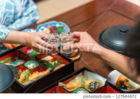 Hands of a couple toasting with cold sake glasses at a banquet 127664972