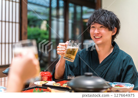 A couple in yukata sipping draft beer while enjoying a banquet 127664975