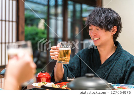 A couple in yukata sipping draft beer while enjoying a banquet A couple in yukata sipping draft beer while enjoying a banquet 127664976